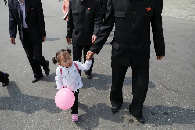 A girl walks with men arriving at the flower exhibition marking the 105th birth anniversary of the country's founding father, Kim Il Sung in Pyongyang, North Korea April 16, 2017. (Photo by Damir Sagolj/Reuters)