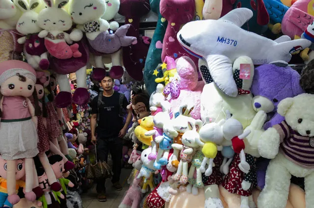 A man looks up as a stuffed toy of Malaysia Airlines MH370 is on sale at a store in Guangzhou, Guangdong province, May 11, 2014. (Photo by Alex Lee/Reuters)