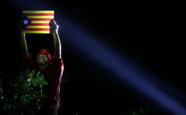 A pro-democracy demonstrator wearing a mask holds an Estelada (Catalan separatist flag) during a protest in Hong Kong's Chater Garden showing their solidarity with the Catalonian independence movement in Spain, in Hong Kong, China, October 24, 2019. (Photo by Ammar Awad/Reuters)