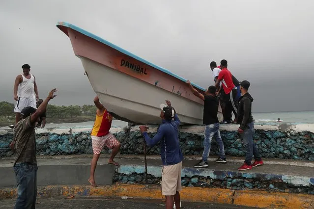 Men take a boat off a beach before the arrival of Tropical Storm Fred in Santo Domingo, Dominican Republic on August 11, 2021. (Photo by Ricardo Rojas/Reuters)