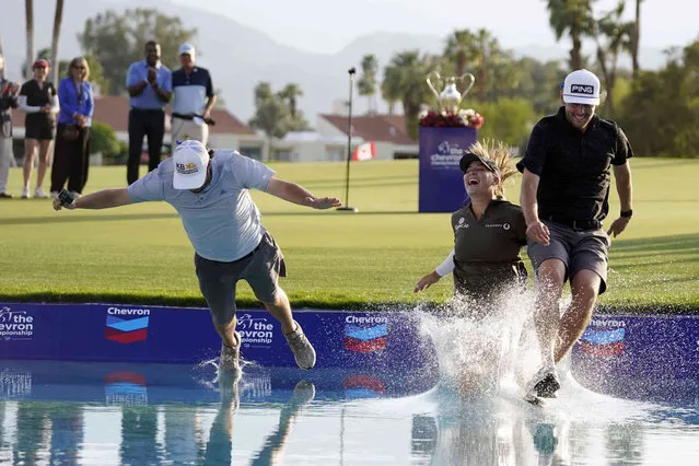 Jennifer Kupcho, center, jumps in the water with her husband Jay Monahan, right, and caddie David Eller after Kupcho's win in the LPGA Chevron Championship golf tournament Sunday, April 3, 2022, in Rancho Mirage, Calif. (Photo by Marcio Jose Sanchez/AP Photo)