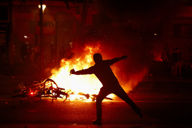 A protester throws a projectile near burning bicycles during clashes with police following partial results in the second round of the early French parliamentary elections, at the Place de la Republique in Paris, France, on July 7, 2024. (Photo by Yara Nardi/Reuters)