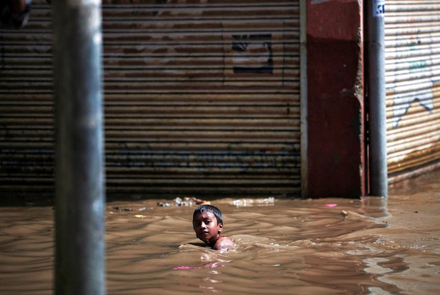 A boy swims in the flooded area near the bank of the overflowing Bagmati River following heavy rains in Kathmandu, Nepal on July 31, 2024. (Photo by Navesh Chitrakar/Reuters)