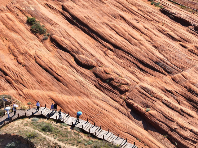 Tourists enjoy wave-like landscape of Danxia landform at Bolang Valley, or the Wavy Valley, on August 13, 2024 in Jingbian Couty, Yulin City, Shaanxi Province of China. (Photo by Liang Shengren/VCG via Getty Images)