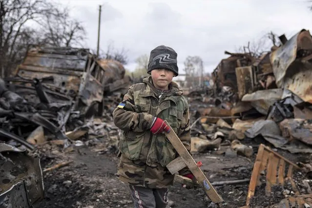 Yehor, 7, stands holding a wooden toy rifle next to destroyed Russian military vehicles near Chernihiv, Ukraine, Sunday, April 17, 2022. Witnesses said multiple explosions believed to be caused by missiles struck the western Ukrainian city of Lviv early Monday as the country was bracing for an all-out Russian assault in the east. (Photo by Evgeniy Maloletka/AP Photo)