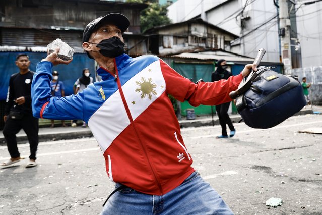 A member of a demolition team throws a rock during clashes with informal settlers during a demolition raid at a shanty town in Pasay City, Metro Manila, Philippines, 01 August 2024. (Photo by Francis R. Malasig/EPA)