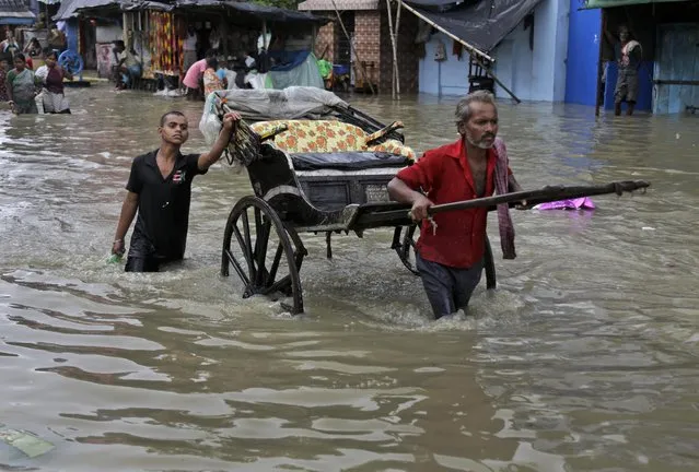 An Indian hand rickshaw puller makes his way through a flooded street in Kolkata, India, Sunday, Aug. 2, 2015. Parts of the city were flooded Sunday after water from the Ganges river rose following monsoon rains. (Photo by Bikas Das/AP Photo)