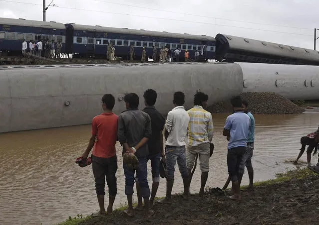 Onlookers stand at the site of a train accident near the town of Harda in Madhya Pradesh state, India, Wednesday, August 5, 2015. (Photo by AP Photo)