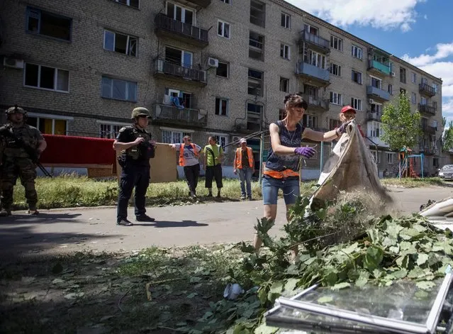 Communal workers clean an area around an apartment building destroyed in a military strike, amid Russia's invasion of Ukraine, in Kurakhove, Ukraine on June 7, 2022. (Photo by Anna Kudriavtseva/Reuters)