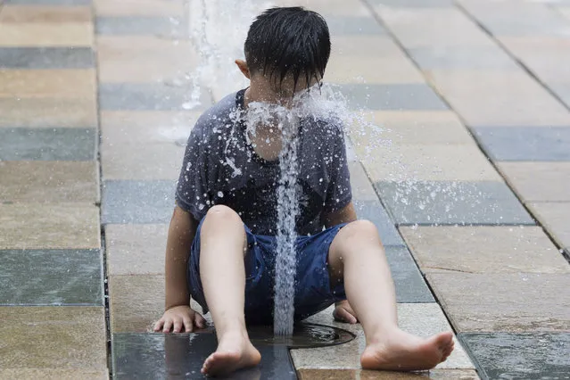 A child is sprayed by a fountain during a hot day in Beijing Wednesday, July 12, 2017. Summer heat routinely rise to the high 30s Celsius (90s Fahrenheit) driving many residents to seek ways to cool off. (Photo by Ng Han Guan/AP Photo)