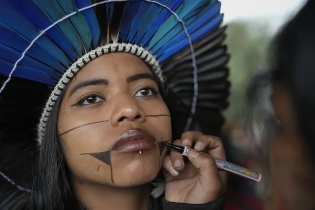 A Guarani Indigenous girl has her face painted in preparation for a demonstration in support of British journalist Dom Phillips and Indigenous expert Bruno Perreira, demanding authorities conduct a thorough investigation into the circumstances leading to their deaths, and do more to protect indigenous lands against illegal miners, loggers, and fishermen, in Sao Paulo, Brazil, Saturday, June 18, 2022. (Photo by Andre Penner/AP Photo)