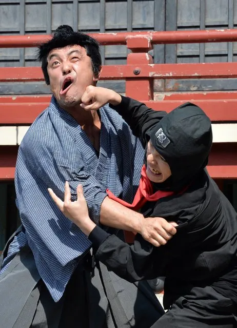 This picture taken on July 16, 2014 shows members of pantomime group Gabez clad in a samurai (R) and ninja (L) costums performing at Asakusa shrine in Tokyo during a press preview for the new bus tour to enjoy ninja acts on the street and the ancient shrine. Japan's travel agency JTB will start the new entertainment bus tour with ninja performance in Tokyo from next month. (Photo by Yoshikazu Tsuno/AFP Photo)