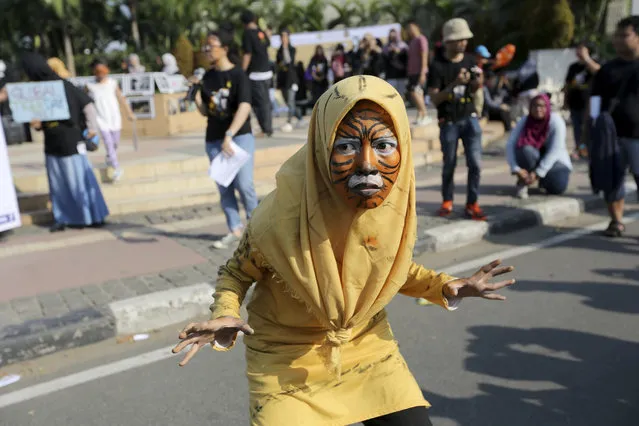 A Muslim activist with face painted to resemble a tiger, takes part in a rally against Sumatran tiger trade that marks the International Tiger Day, in Jakarta, Indonesia, Sunday, July 30, 2017. Sumatran tiger is the world's most critically endangered tiger subspecies with fewer than 400 remain in the wild and may become extinct in the next decade due to poaching and habitat loss. (Photo by Tatan Syuflana/AP Photo)