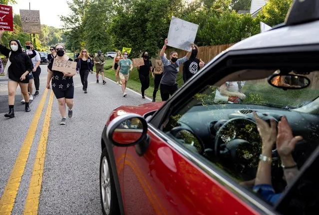 A woman claps in her car as abortion rights activists march to the home of United States Supreme Court Justice Samuel Alito in Alexandria, Virginia, U.S., June 27, 2022. (Photo by Evelyn Hockstein/Reuters)