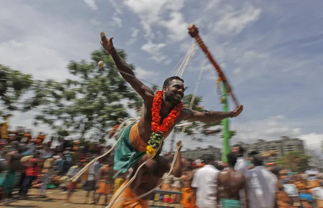 A Hindu devotee hanging from a pole with hooks pierced to his back is rotated by another as he performs a ritual on the occasion of “Aadi” fest in Chennai, India, Sunday, August 9, 2015. Aadi is considered a holy month by Tamils and is celebrated with rituals worshipping Hindu goddess Durga. (Photo by Arun Sankar K./AP Photo)
