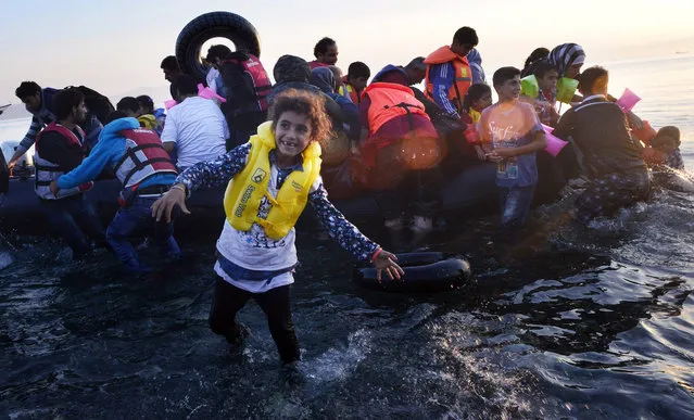A Syrian child smiles as refugees arrive at a beach on the Greek island of Kos after crossing a part of the Aegean sea from Turkey to Greece in a dinghy on August 15, 2015 in Kos, Greece. (Photo by Milos Bicanski/Getty Images)