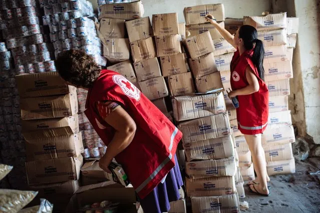 Members of International Committee of the Red Cross check products in a storehouse after Ukrainian convoy delivered humanitarian aid for eastern Ukrainian regions, in town Starobelsk, Ukraine, 15 August 2014. Ukraine sent its own aid convoy to the region. Iryna Herashchenko, an aide to President Petro Poroshenko, said that a number of lorries have arrived in the Luhansk region and that Red Cross workers had begun unloading them. (Photo by Roman Pilipey/EPA)