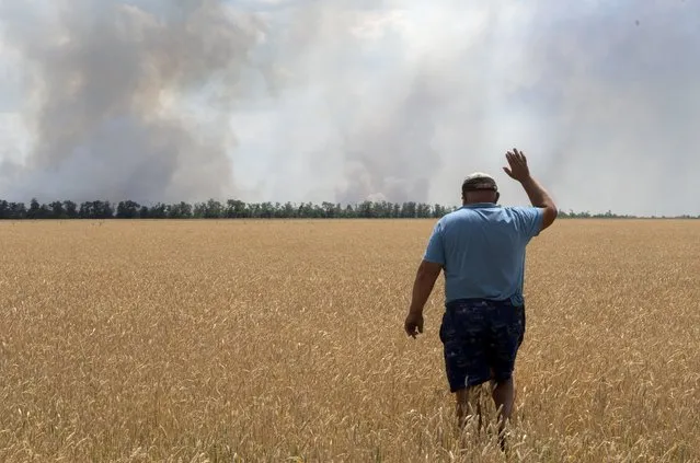 A farmer reacts as he looks at his burning field caused by the fighting at the front line in the Dnipropetrovsk region, Ukraine, Monday, July 4, 2022. (Photo by Efrem Lukatsky/AP Photo)