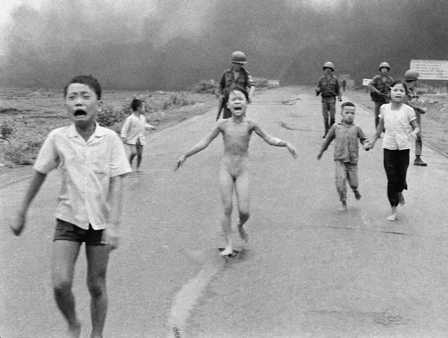 South Vietnamese forces follow after terrified children, including 9-year-old Kim Phuc, center, as they run down Route 1 near Trang Bang after an aerial napalm attack on suspected Viet Cong hiding places on June 8, 1972. (Photo by Nick Ut/AP Photo)