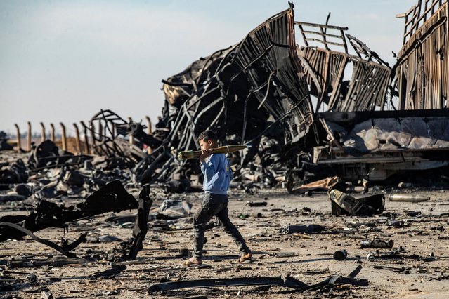 A boy carries an unexploded Rocket Propelled Grenade (RPG) at the site of the previous evening's Israeli airstrike that targeted shipments of weapons that belonged to Syrian government forces in Qamishli, in mainly Kurdish northeastern Syria, on December 10, 2024. The UN special envoy for Syria called on Israel on December 10 to halt its military movements and bombardments in Syria, after a war monitor reported 300 air strikes since the fall of president Bashar al-Assad. (Photo by Delil Souleiman/AFP Photo)