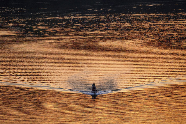 A single bass fishing boat cruises along the Potomac River at sunset in Washington, Wednesday evening, April 8, 2020. Boat traffic on the river is thinner than usual as people practice social distancing during the coronavirus outbreak. (Photo by J. David Ake/AP Photo)