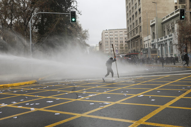 A jet of water is released on demonstrators during a protest marking the 49th anniversary of the 1973 Chilean military coup, in Santiago, Chile, September 11, 2022. (Photo by Carlos Vera/Reuters)