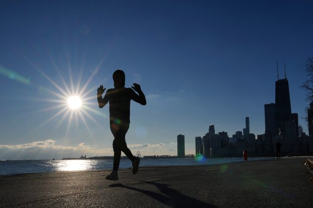 A lone jogger traverses the Lake Michigan shoreline on a bike and running path in below freezing temperatures Friday, January 3, 2025, in Chicago. (Photo by Charles Rex Arbogast/AP Photo)