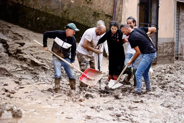 People help an elderly woman after heavy rains and deadly floods hit the central Italian region of Marche, in Cantiano, Italy on September 16, 2022. (Photo by Yara Nardi/Reuters)