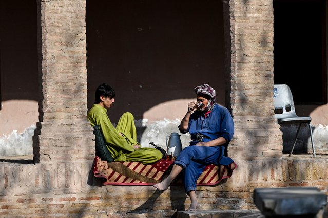 Afghan workers take a break in front of a shop in the Herat citadel, also known the citadel of Alexander and locally known as Qala Iktyaruddin, in Herat on December 23, 2024. (Photo by Wakil Kohsar/AFP Photo)