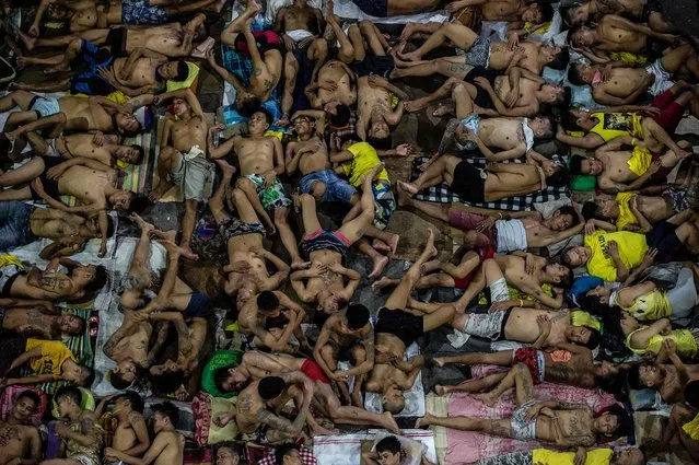 In this photo taken on July 19, 2016 inmates sleep on the ground of an open basketball court inside the Quezon City jail at night in Manila. (Photo by Noel Celis/AFP Photo)