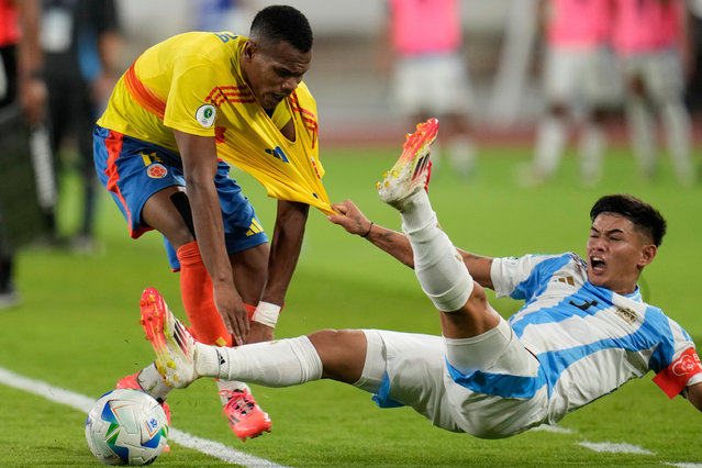Argentina's Julio Soler, right, grabs onto the jersey of Colombia's Andy Batioja, as he falls on the pitch during a South American U-20 Championship final round soccer match in Caracas, Venezuela, February 10, 2025. (Photo by Matias Delacroix/AP Photo)