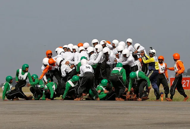 Members of the Indian army’s motorcycle display team, ASC Tornadoes, fall to the ground after attempting to create a world record for the most people on a single moving motorcycle at the Yelahanka Air Force station on November 19, 2017. (Photo by  Abhishek Chinnappa/Reuters)