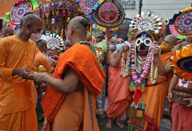 Hindu monks, wearing protective face masks, carry an idol of Hindu Lord Jagannath as part of a ritual after ISKCON (International Society of Krishna Consciousness) cancelled the annual Rath Yatra, or chariot procession, amidst the coronavirus disease (COVID-19) outbreak, in Kolkata, India, June 23, 2020. (Photo by Rupak De Chowdhuri/Reuters)