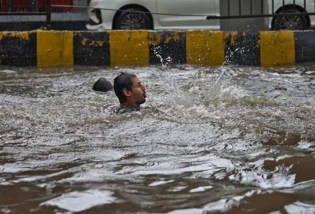 A man plays in a flooded road during heavy rains in Mumbai, India, July 4, 2020. (Photo by Hemanshi Kamani/Reuters)