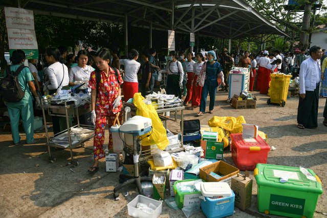 Medical workers and people walk past boxes of medical material placed in the compound of a hospital in Naypyidaw on March 28, 2025, after an earthquake in central Myanmar. (Photo by Sai Aung Main/AFP Photo)