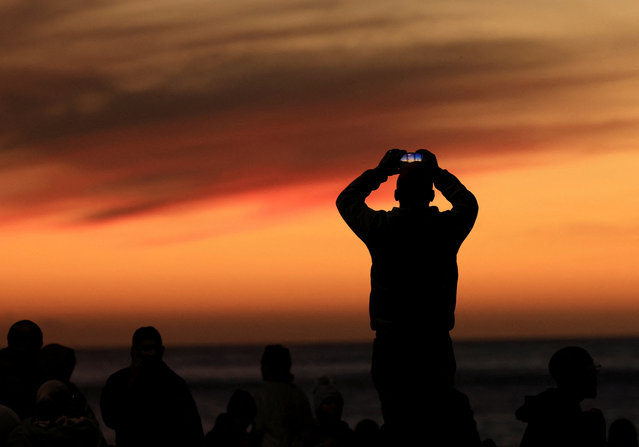 A man holds his phone while the sun sets, as people await for the sighting of the moon, ahead of Eid al-Fitr, marking the end of the Muslim holy month of Ramadan, in Cape Town, South Africa, on March 30, 2025. (Photo by Esa Alexander/Reuters)