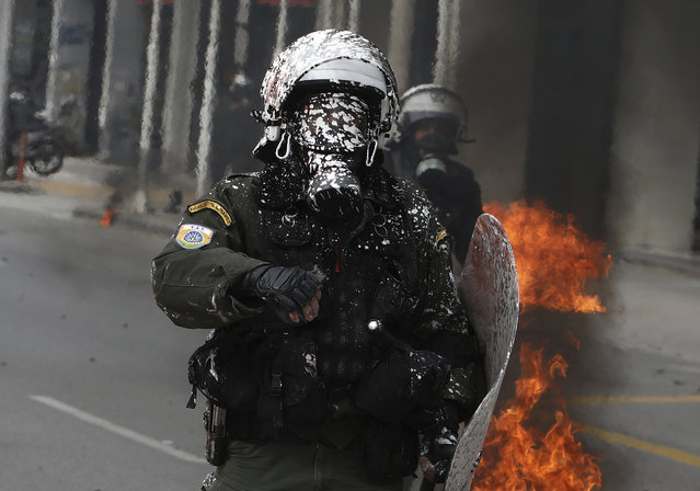 A riot policeman covered, with white paint thrown by protesters, operates during clashes in the northern port city of Thessaloniki, Greece, Wednesday, February 28, 2024. Widespread strikes in Greece disrupted transport services Wednesday, halting ferries and trains, in protests timed to coincide with the anniversary of a deadly rail crash a year ago. (Photo by Giannis Papanikos/AP Photo)