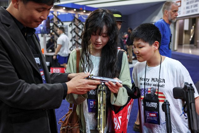 Attendees hold a gun at a booth at the NRA annual meeting in Atlanta, Georgia, U.S. April 26, 2025. (Photo by Jeenah Moon/Reuters)