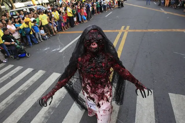 A participant wearing a costume walks past spectators during a Halloween Parade in Marikina city, east of Manila October 30, 2014. (Photo by Romeo Ranoco/Reuters)