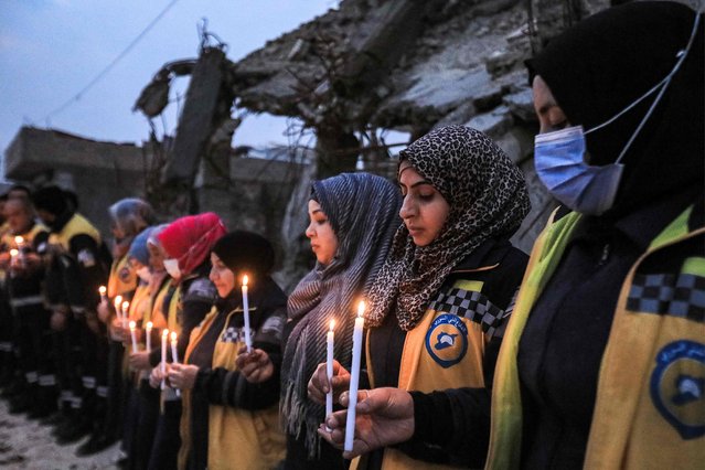 Members of the Syrian Civil Defence (also known as the White Helmets) stand in a candle-lit remembrance vigil with survivors of the February 6, 2023 earthquake that devastated northern Syria and Turkey, marking the first anniversary of the disaster by some of the destroyed buildings in the town of Jindayris in the northwest of Syria's Aleppo province on February 3, 2024. (Photo by Bakr Alkasem/AFP Photo)
