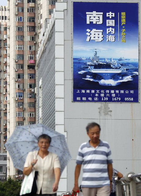People walk past a poster that reads “The South China Sea is China's inland sea” in Shanghai, China, Monday, September 12, 2016. The Chinese and Russian navies launched eight days of war games in the South China Sea on Monday, in a sign of growing cooperation between their armed forces against the backdrop of regional territorial disputes. (Photo by Chinatopix via AP Photo)