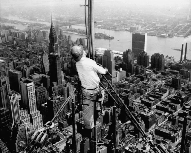 High over Manhattan, a workman is busy on construction of the Empire State Building's new 217 foot multiple television tower in this September 28, 1950 file photo. The tower increased the building's height to 1,467 feet. Born in the Great Depression, it has weathered economic hardship, world war, labor strikes, murder, terrorist fears and yes, even its own plane crash. (Photo by AP Photo)
