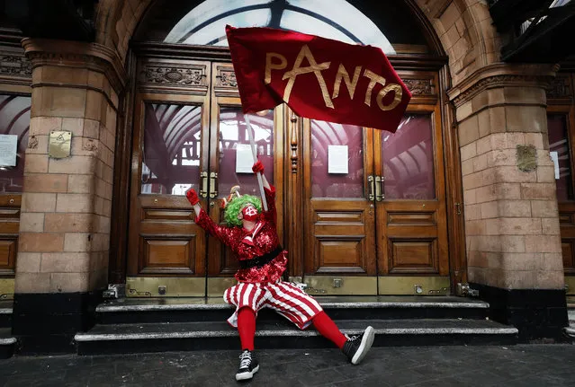 An actor dressed as pantomime dame waves a flag at the entrance of a theatre before marching on Parliament to demand more support for the theatre sector amid the COVID-19 pandemic, in London, Wednesday, September 30, 2020. (Photo by Frank Augstein/AP Photo)