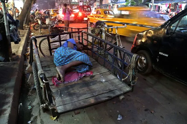 An Indian man sleeps on a cart as traffic moves past him in Kolkata, India, Thursday, November 27, 2014. Outdoor air pollution kills millions worldwide every year, according to the WHO, including more than 627,000 in India. (Photo by Bikas Das/AP Photo)