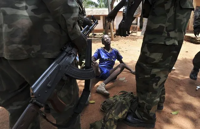 Rebels of the Seleka coalition arrest a man, who was wearing military fatigues and claiming to belong to the Seleka movement, suspected of looting in Bangui, Central African Republic, on March 26, 2013. CAR strongman Michel Djotodia was set to unveil a new government that day after declaring he would rule by decree following the latest coup in the notoriously unstable nation. Looters were on the rampage in the capital Bangui after Djotodia's Seleka rebel coalition seized control in a weekend assault that forced President Francois Bozize into exile and was condemned by the international community. (Photo by Sia Kambou/AFP Photo)