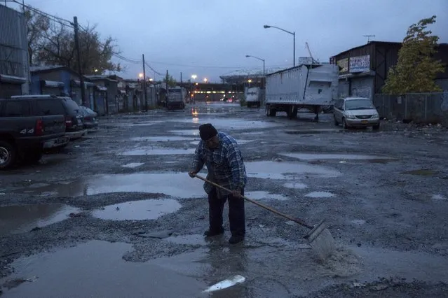 A man attempts to clear puddles in the street following heavy rain in the Willets Point area of Queens in New York October 28, 2015. (Photo by Andrew Kelly/Reuters)