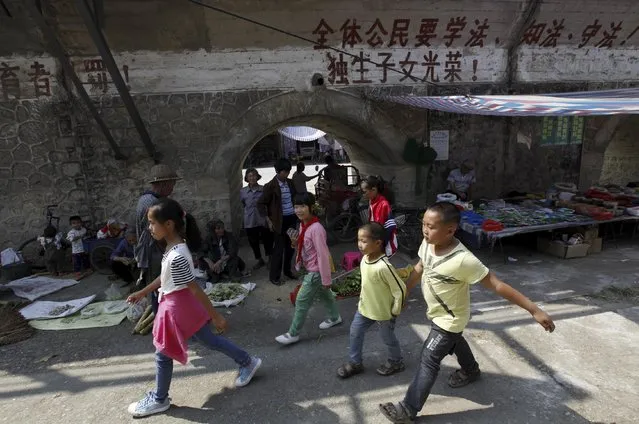 Children walk past a one-child policy slogan written on a wall, which partially reads "All citizens must observe the law, a single child is glorious" at a market in Futang village of Liuzhou, Guangxi Zhuang Autonomous Region, China, October 19, 2015. China's top family planning authority said on Friday the central government will leave it to the provinces to hash out the details of implementing a new policy allowing couples to have two children. (Photo by Reuters/Stringer)