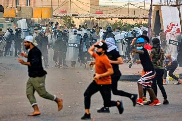 Anti-government protesters throw stones towards security forces in Basra, Iraq, Sunday, November 1, 2020. (Photo by Nabil al-Jurani/AP Photo)