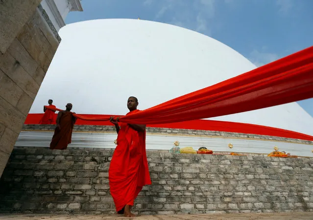 Buddhist monks carry a holy red cloth on top of the Ruwanwelisaya Stupa, during a poya day religious ceremony in Anuradhapura, Sri Lanka October 15, 2016. (Photo by Dinuka Liyanawatte/Reuters)