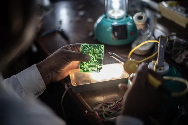 Indian villager Shayudan Gujar, 42, tests a circuit board for a solar lamp in a class held as part of the Barefoot Solar Project to bring solar powered lighting to rural areas on March 25, 2023 in Solawata, India. (Photo by Rebecca Conway/Getty Images)